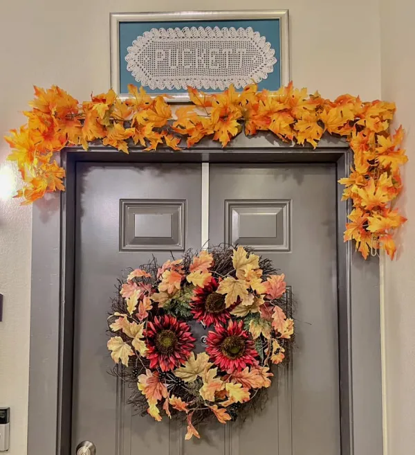 A resident's front door decorated with a fall wreath and leaf garland