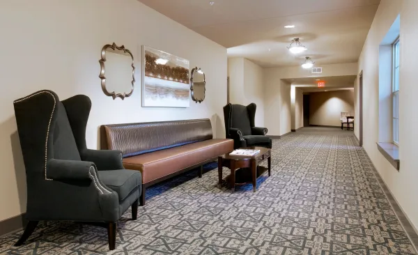 A wide, carpeted interior corridor lined with apartment doors